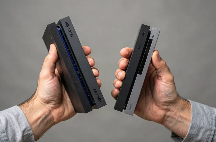 Mains tenant une PS4 Fat et une PS4 Slim pour comparer leur épaisseur et leur format physique